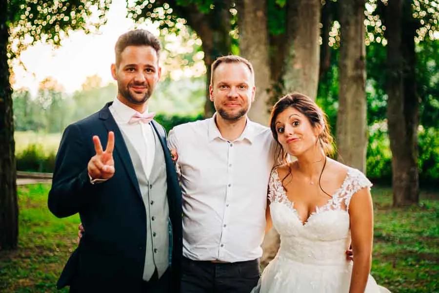 Un couple de mariés qui pose avec un photographe de mariage